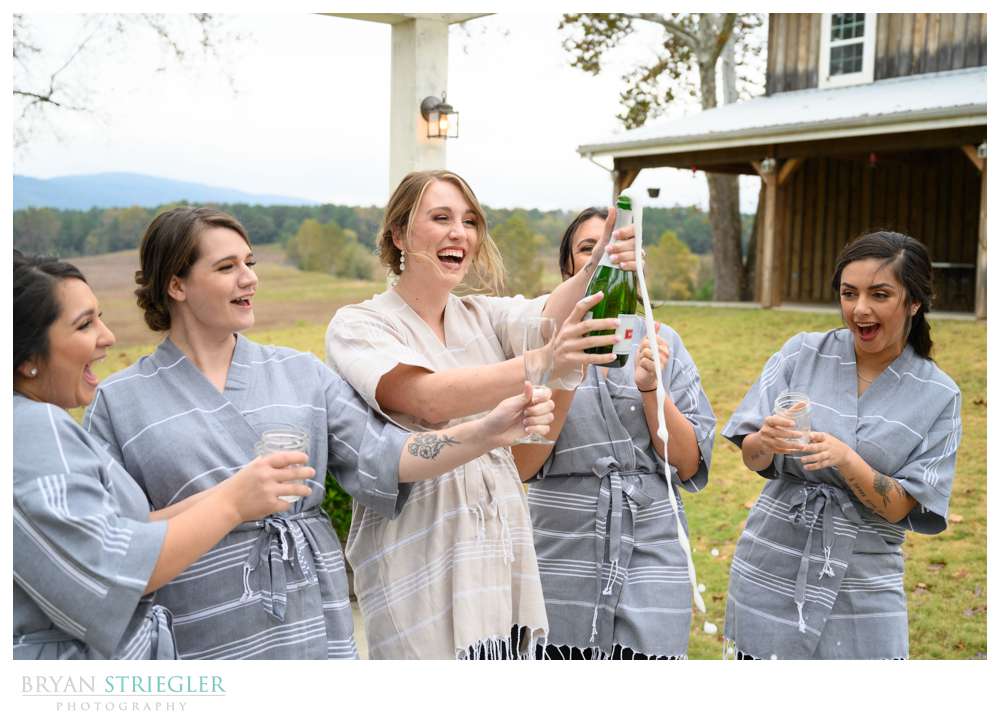 bride popping champagne with bridesmaids